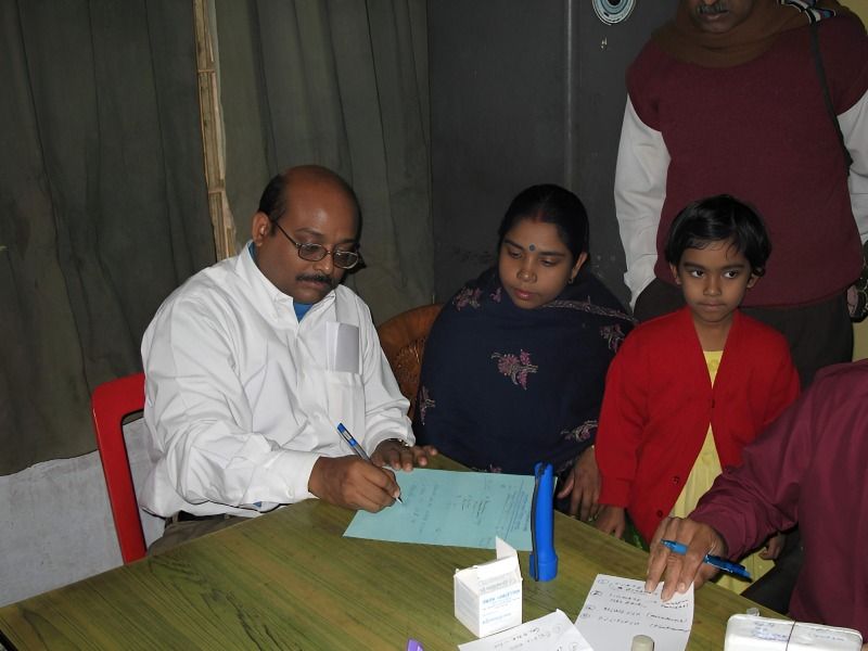 Physician writing a prescription for a family at a camp